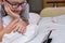 A preteen boy in glasses lying on a bed and watching video on smartphone