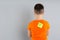 Preteen boy with KICK ME sticker on back against light grey background. April fool`s day