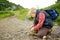 Preteen boy lacing up shoes while tracking on road in mountains valley. Family hiking with kids