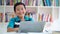 Preteen boy with laptop smiling in library