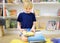 A preteen boy leafing through a book while sitting at the bookshelves at home, in a school library or bookstore. Smart kid reading