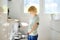 A preteen boy is loading dirty dishes into the dishwasher. The child does his household chores