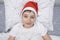 A preteen boy lying in bed in santa hat during christmas eve night and waiting for gifts and miracles, happy xmas and