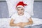 A preteen boy lying in bed in santa hat during christmas eve night and waiting for gifts and miracles, happy xmas and new year
