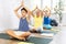 Preteen boy practicing lotus pose of yoga in light fitness room