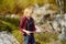 Preteen boy in red shirt is exploring nature and having fun during hiking in mountains valley on sunny day. Active leisure for