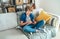 Preteen boy sitting at home on cozy sofa dressed casual jeans and new sneakers listening to music and chatting using wireless head