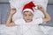 A preteen boy sleeping in bed in santa hat during christmas eve night and waiting for gifts and miracles, happy xmas and new year