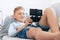 Preteen boy use gamepad with smartphone plays games lying on the cozy sofa in the home living room