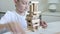 A preteen caucasian boy making tower using wooden blocks, he is concentrated and mindful . Child playing games for