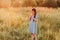 Preteen caucasian girl with long brown hairs standing in summer meadow alone. Little girl deep in thoughts