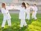 Preteen children practicing in pairs martial arts movements on green sports field