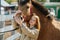 Preteen ginger girl holding horse`s snout, touching horse`s head with hers