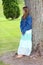 Preteen girl leaning against a tree