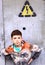 preteen handsome boy on front of the door with electricity warning sign