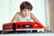 Preteen handsome boy play with meccano toy train and railway sta