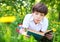 Preteen handsome keen boy red and old book in the summer park wi