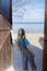 Preteen happy girl opening wooden door to sunny seaside, follow me shot, hello summer concept