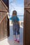 Preteen happy girl opening wooden door to sunny seaside, follow me shot, hello summer concept