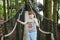 Preteen kid boy walking on high tree-canopy trail with wooden walkway and ropeways on Hoherodskopf in Germany. Happy