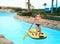 Preteen little boy in aqua park swim in rubber boat with row