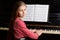 Preteen little girl musician sitting at piano and looking to the camera.