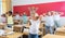 Preteen schoolchildren with teacher performing physical exercises in classroom