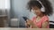 Pretty Afro-American child wearing earphones and listening to music on cellphone