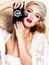 Pretty as a picture. A glamourous young woman in retro attire holding a camera while posing against a paisley background