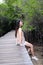 Pretty Asain girl is smiling and sitting on wooden bridge in the tropical mangrove forest at Thailand