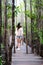 Pretty Asain girl is smiling and standing on wooden bridge in the tropical mangrove forest at Thailand