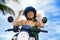 Pretty Asian Chinese girl showing key of new motorbike wearing motorcycle safety helmet smiling proud in scooter buying and rental