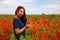 Pretty asian girl with long hair in blue dress in field of poppy seed flower on green stem on natural background, summer