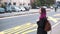 Pretty asian hipster girl waiting at a bus stop on a busy street. Pink colored hair charming millenial using public city