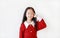 Pretty asian little child girl in Scarlet red dress closed eyes with thinking expression and pointing index finger to head. Kid