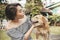 A pretty asian woman wearing an off shoulder top bonds with her golden furred dog while both are sitting on a bench