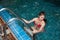 Pretty Asian woman wearing red bikini swim and standing at stair at swimming pool.