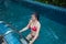 Pretty Asian woman wearing red bikini swim and standing at stair at swimming pool.