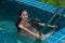 Pretty Asian woman wearing red bikini swim and standing at stair at swimming pool.