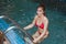 Pretty Asian woman wearing red bikini swim and standing at stair at swimming pool.