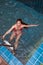 Pretty Asian woman wearing red bikini swim and standing at stair at swimming pool.