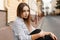 Pretty attractive young woman in a vintage black and white striped blouse in stylish jeans with elegant velvet necklaces sits