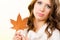 Pretty autumnal girl with maple leaf in hand