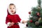 Pretty baby decorating Christmas tree isolated