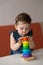 Pretty baby girl play with wooden colourful pyramid toy.