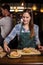 Pretty barista putting sandwich in a dish