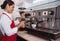 Pretty barista steaming jug of milk at coffee machine