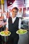 Pretty barmaid holding plates of salads