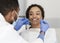 Pretty black lady looking at her dentist with smile