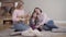 Pretty blond Caucasian girl playing ukulele for mother and young sister at home. Talented teenager entertaining family